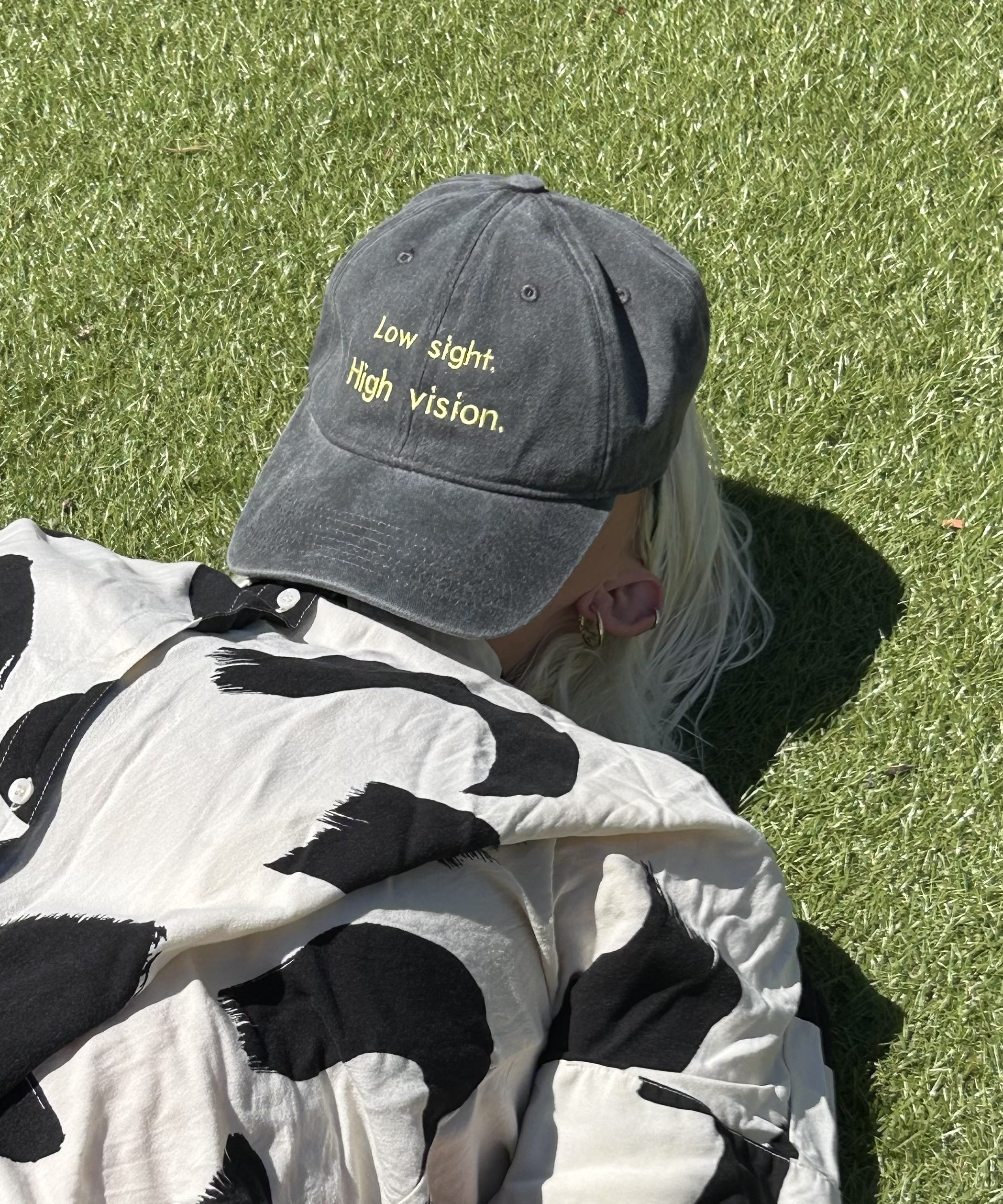 Black and yellow low sight high vision cap on someone laying down propped on face