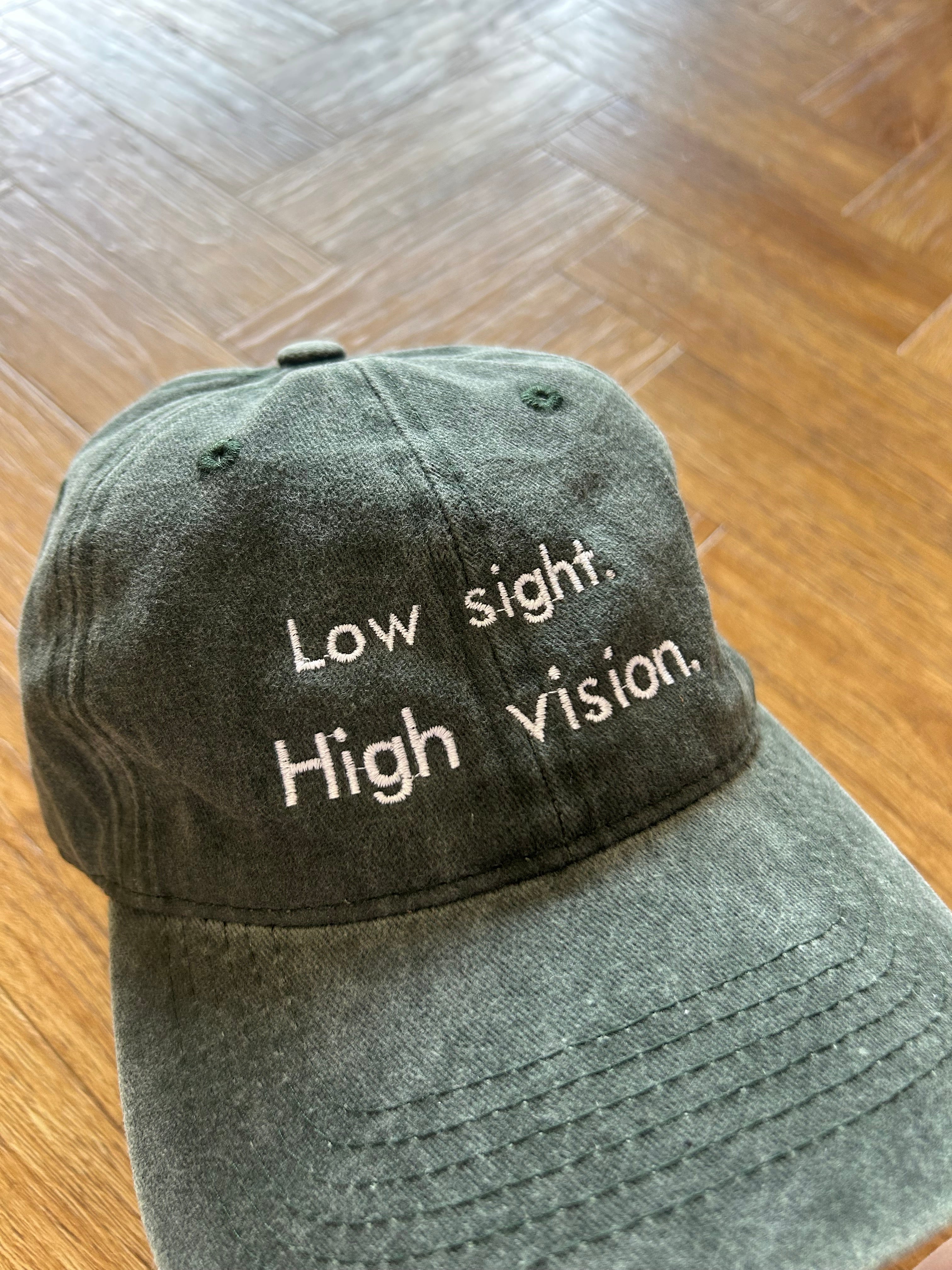 Low sight. High vision. Washed cotton cap in green / black with white embroidery