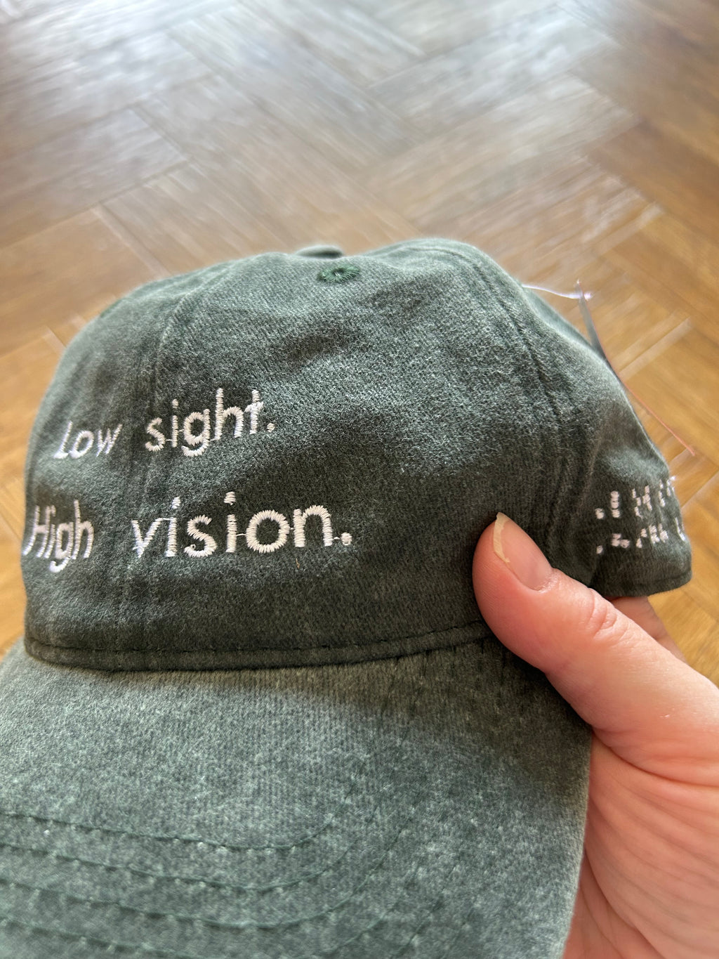 Low sight. High vision. Washed cotton cap in green / black with white embroidery